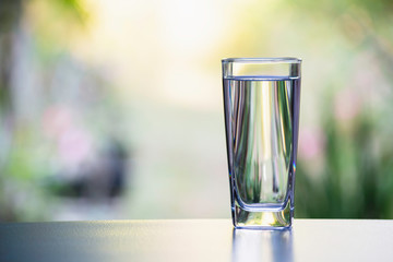 Water in the glass on table with nature background