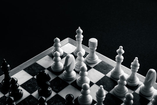 White chess figures defend against black figures on chessboard