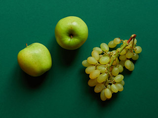 Above view of isolated set of a green apple with a bunch of sweet seedless grapes in studio with...