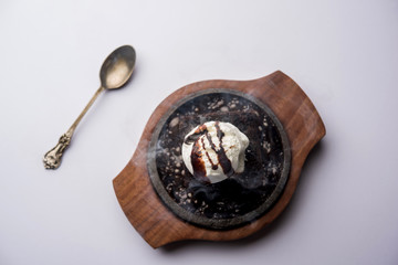 sizzling chocolate brownie is a sweet dish made using scoop of ice-cream on top served with a generous pouring of melted chocolate. server hot. selective focus