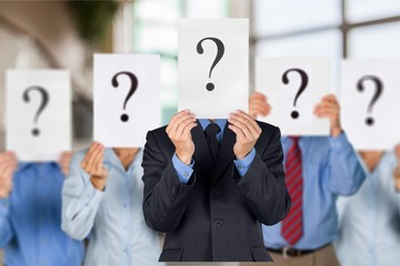 Business people with question marks on face on background