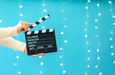Movie slateboard clapper on a shiny light blue background