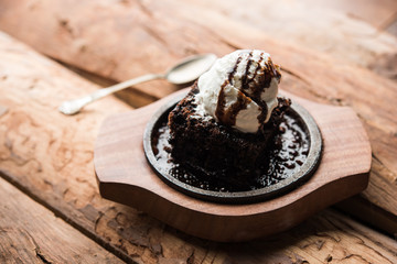 sizzling chocolate brownie is a sweet dish made using scoop of ice-cream on top served with a generous pouring of melted chocolate. server hot. selective focus