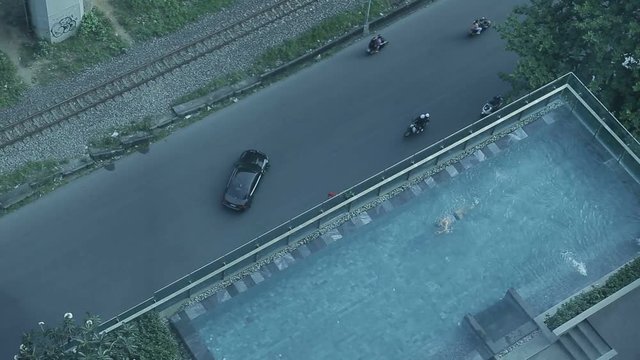 man swims in the hotel’s outdoor pool at sunny day