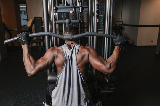 Black Man Exercising On Machine In Gym