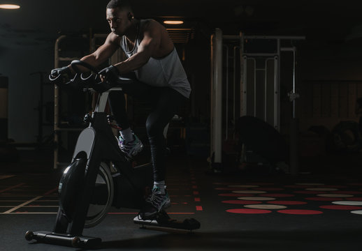 Serious black man on exercise bike in gym