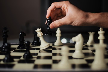 Tablero de ajedrez con varias fichas encima, donde aparece una mano moviendo al alfil y matando a la reina de las fichas blancas.