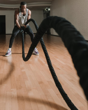 Black Guy Exercising With Ropes In Gym