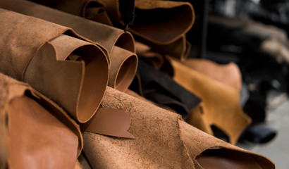 Different pieces of leather in a rolls. The pieces of the colored leathers. Rolls of natural brown red leather. Raw materials for manufacture of bags, shoes, clothing and accessories. - Powered by Adobe
