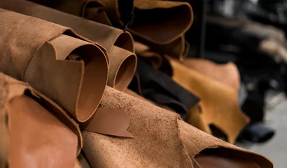 Deurstickers Different pieces of leather in a rolls. The pieces of the colored leathers. Rolls of natural brown red leather. Raw materials for manufacture of bags, shoes, clothing and accessories. © Volodymyr