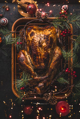 Whole roasted turkey in roasting pan for Christmas dinner served on dark background with winter...