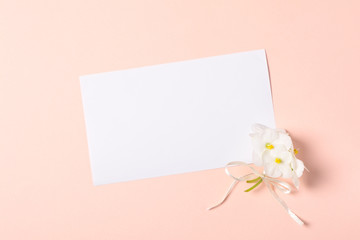 Bouquet of violet flowers (viola) and empty greeting card on pink paper background. Valentine's day celebration concept. Top view. Flat lay. Mock-up