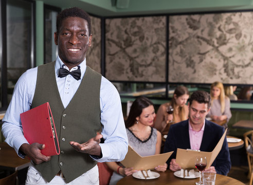 African male administrator welcoming restaurant guests