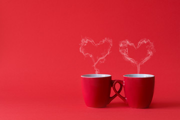 Cups of tea or coffee with steam in two heart shape on red background. Valentine's day celebration...