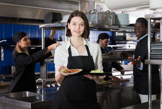 Waitress holding meals in restaurant kitchen
