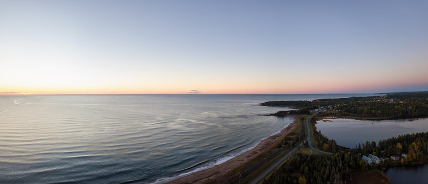 Aerial panoramic view of a Beautiful Sandy Beach on the Atlantic Ocean Coast during a vibrant sunrise. Taken near in Pabos Mills, Quebec, Canada.