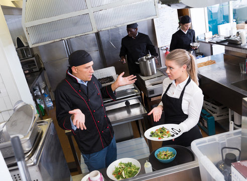Waitress with dish talking with puzzled chef