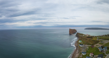 Aerial panoramic view of a beautiful modern town on the Atlantic Ocean Coast during a cloudy sunset. Taken in Perc&eacute;, Quebec, Canada.