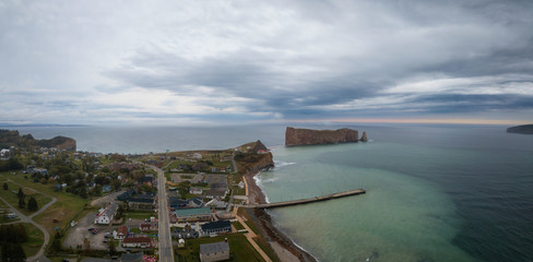 Aerial panoramic view of a beautiful modern town on the Atlantic Ocean Coast during a cloudy sunset. Taken in Percé, Quebec, Canada.