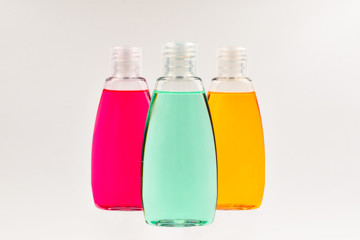 Three plastic bottles with liquid yellow, green and red soap.