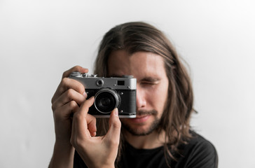 Handsome young bearded man with a long hair and in a black shirt holding vintage old-fashioned film...