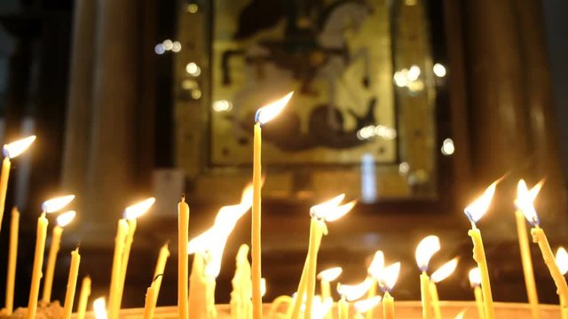 Wax candles burn in the dark in the Orthodox Church framed with an ancient icon