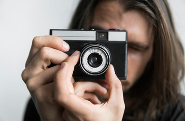 Handsome young bearded man with a long hair and in a black shirt holding vintage old-fashioned film...
