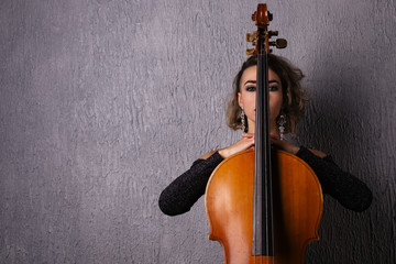 Portrait of a young sad woman. Part of the face is covered by the neck of the cello
