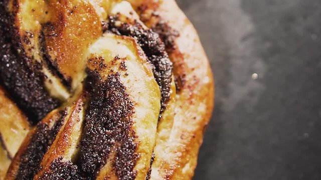 Swirl bun with poppy seeds, top view. Poppy seed braided or roll bread on slate, dolly shot.