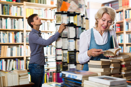 Positive mature woman reading book in book shop