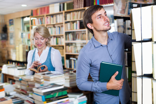 Young man choosing new book from many