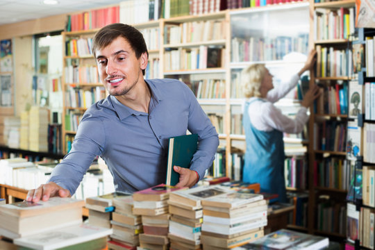 Young smiling male customer holding new book