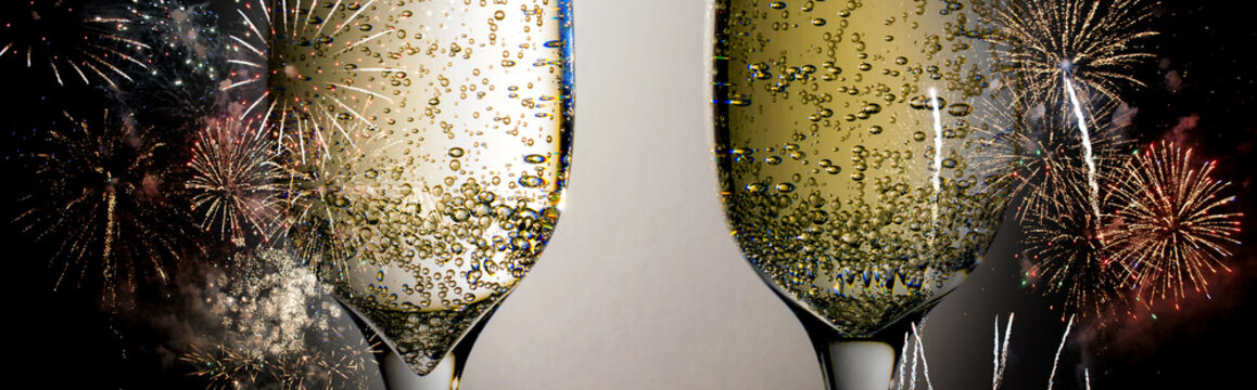 Two glasses of wine sizzling champagne with bubbles close-up on the background of colorful fireworks