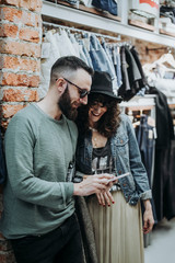 Two friends with smartphone at the fashion shop