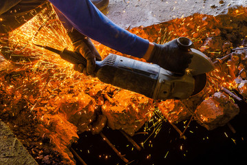 Male worker saws a disk grinding saw armature into a reinforced concrete panel, the destruction of...