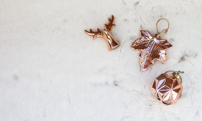 New Year or Christmas decorations on white snow background. Rose gold New Year decorations. Can be used as wallpaper or greeting card. Copy space, top view.