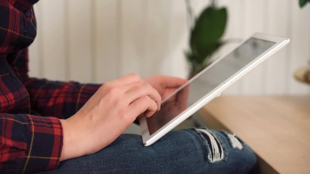 Woman scrolling pages on tablet pc, browsing social media, hands close-up