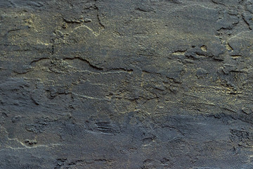 Dark rough background texture with a touch of golden color