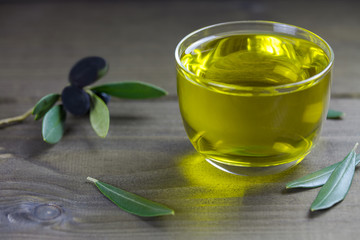 Olive oil and olive branch on the wooden background, apulian olive oil, close up