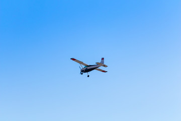 Fototapeta na wymiar Small private aircraft flying away in blue sky