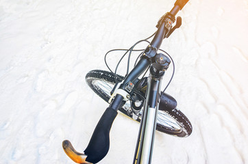 First-person view of cyclist in the snowy road. Mountain bike handlebar top view