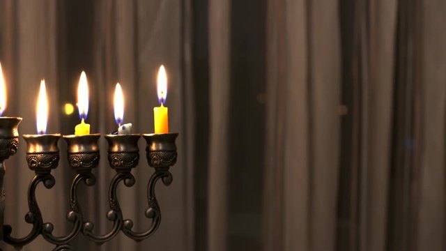 Last eighth day of the Jewish holiday Hanukkah. Nine Hanukkah candles are burning on light curtain background. Selective focus. Camera moves right. 4k