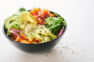 poke bowl with salmon, avocado, cucumber, arugula, broccoli, rice, carrot and sweet onions isolated over white background. side view