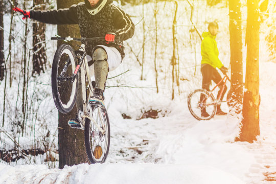 Bike rider flies through the air. Mountain biking on trails in a snowy forest. Extreme winter sport.