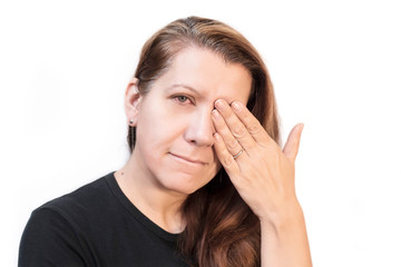 A woman with a suffering face on a light background holds her hand for a sick eye. The woman became ill with a conjunctiva