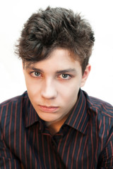 Vertical portrait of an angry teenager in a dark shirt on a light background