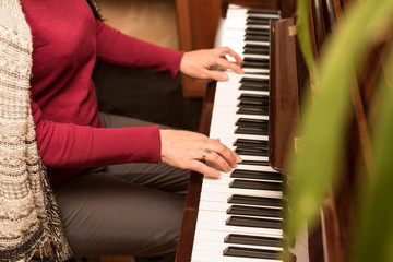 An adult woman playing at home on a piano. A woman loves to rest while playing the piano old songs of her youth