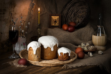 On the old wooden table, covered with a rough cloth, there are cupcakes, a candle, a willow, painted eggs lie to celebrate Holy Easter.