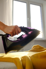 Fototapeta premium Girl ironing clothes at home a yellow jacket