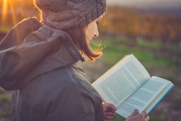 girl reading book at park in autumn sunset light